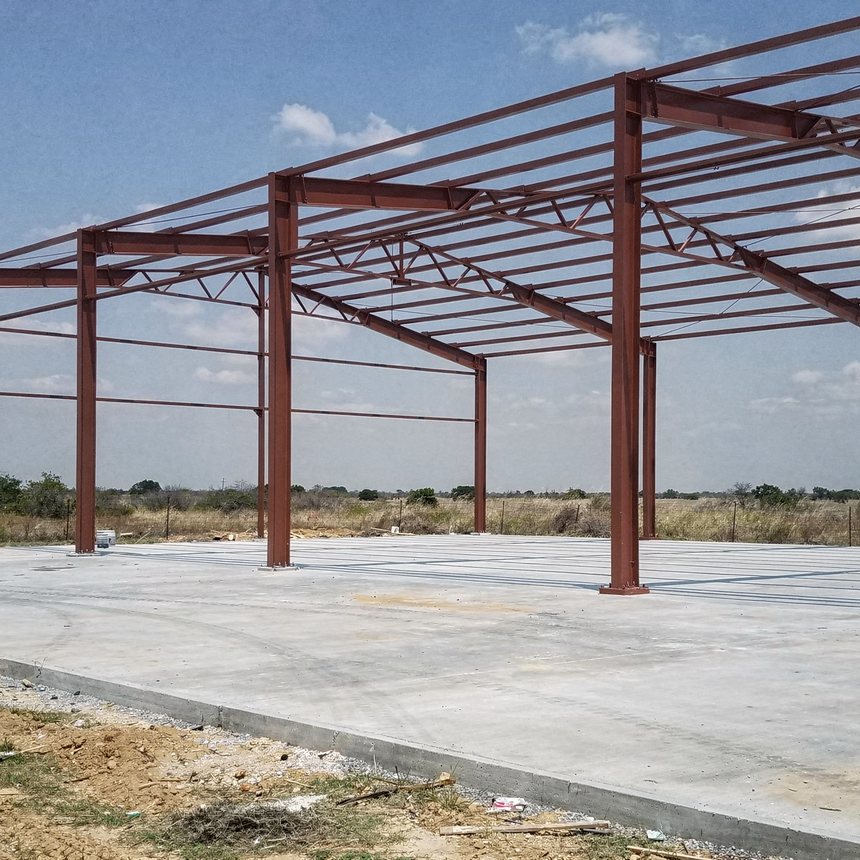Red-iron steel frame being raised on a concrete slab in Houston, TX